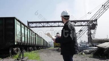 铁路交通检查员在对讲机上烦躁地交谈。 戴着蓝图计划的白盔铁路工人